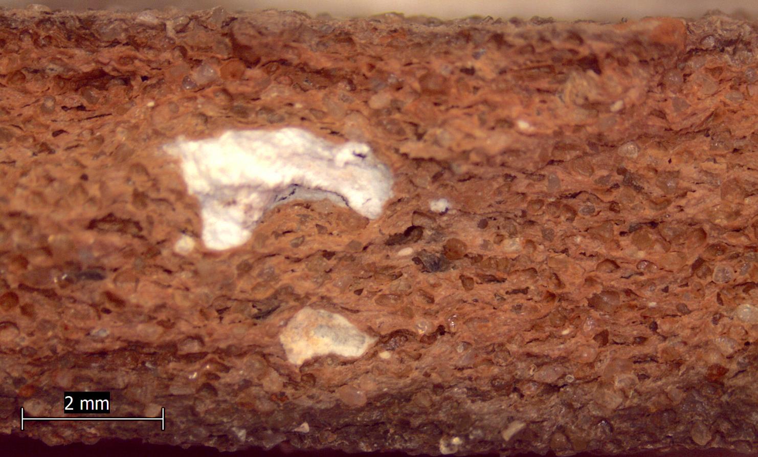 Photo macroscopique d’une cassure de pot, avec présence de quartz, oxydes et calcaires visibles à l’œil nu.