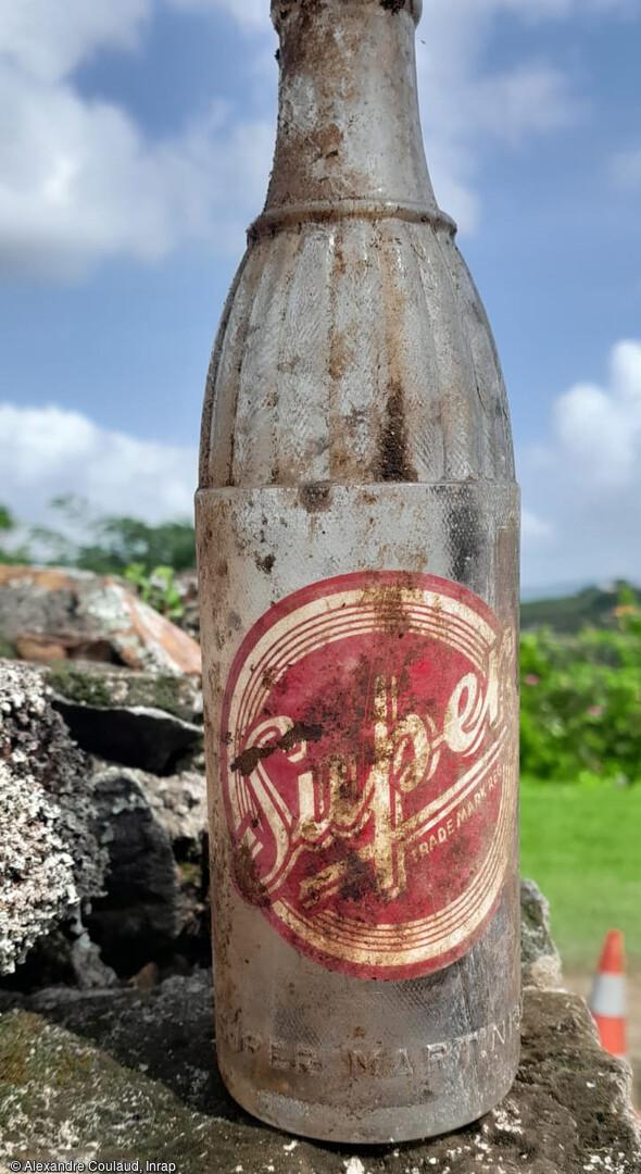 Bouteille en verre de soda "Super" attribuable aux années 1950 provenant d'une ancienne habitation-boutique fouillée aux Trois-Îlets, 2023.