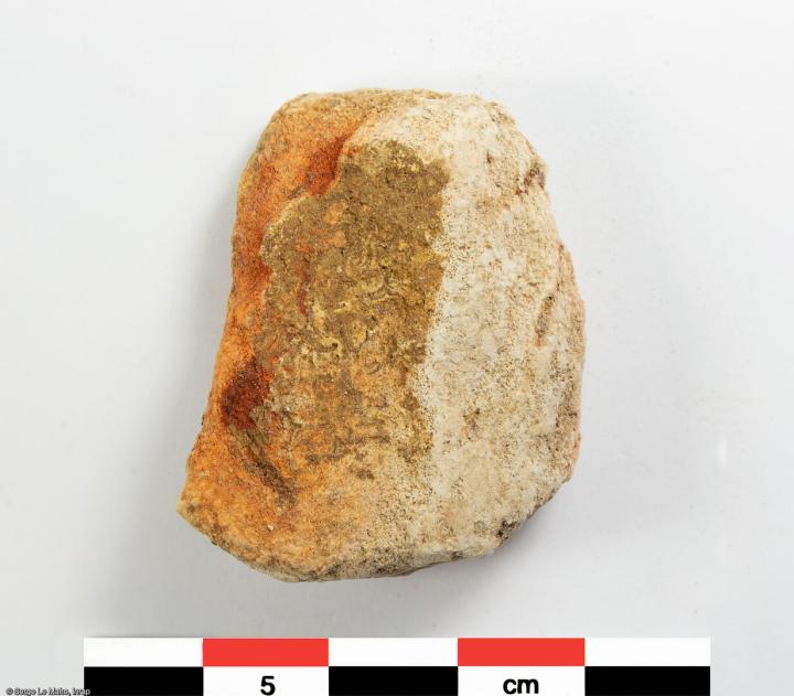 Galet imprégné de colorant ferrugineux découvert sur le site de fouille de Louviers (Eure), en 2023. Des vestiges du Paléolithique y ont été mis au jour.