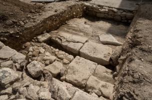 Une chaussée dallée antique équipée d'un caniveau borde le bâtiment à la mosaïque antique découverte à Uzès (Gard), 2017.