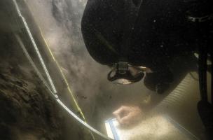 Dans le lac de Sanguinet, réalisation d'un relevé de la stratigraphie d'un sondage en eau très sombre.