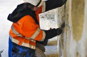 Enlèvement des enduits récents sur un des murs du couvent des Jacobins à Rennes (Ille-et-Vilaine), 2012.  Cette opération permet de révéler les anciennes maçonneries de l'édifice dans le cadre de l'étude du bâti. 
