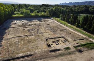 Le mausolée au milieu des parcelles cultivées avec en arrière-plan la villa, IIe-Ve s. de notre ère, Saint-Rémy-de-Provence (Bouches-du-Rhône), 2012.Les vestiges dégagés appartiennent à la partie résidentielle de la villa. Les différents bâtiments sont éd