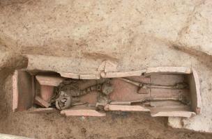 Vue de l'intérieur du coffrage en tuiles de la tombe à libations, Ier-IIIe s. de notre ère, Portbail (Manche), 2012.Une jeune femme y est inhumée avec deux pièces de monnaie en bronze, expression du rite de "l'obole à Charron". Sur la gauche, le coussin c