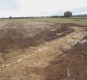 Vue générale de l'aqueduc.  Les dalles de couverture de la canalisation au tracé sinueux manquent par endroits, probablement entraînées par les labours