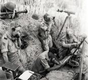 Tranchée d’observation de l’artillerie canadienne (Potenza, Italie, 24 septembre 1943), offrant des caractéristiques similaires à celle de Blainville-sur-Orne. Le chef de pièce est entouré d’un observateur au télémètre, allongé hors de la tranchée, d’un pointeur reportant les coordonnées de tir sur carte, et de deux transmetteurs. Deux hommes accroupis sont installés sur la banquette qui borde la tranchée du côté de l’ennemi.