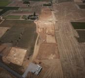 Vue aérienne depuis le nord-est du décapage du site du Péras. On distingue les trois secteurs de fouille : Péras 2, au premier plan à gauche, et les deux autres, qui constituent  Péras 1, en haut de l'image de part et d'autre d'un chemin orienté nord-ouest/sud-est. Le Péras, Mauguio (Hérault), 2013. © Archéodrone, Inrap